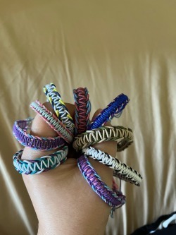 A hand clutching several handmade bracelets